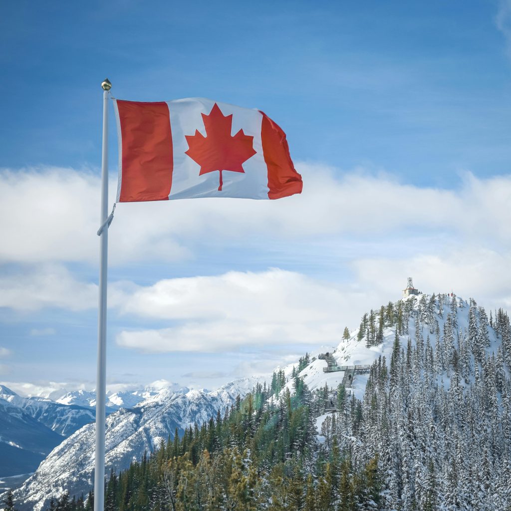 pexels-photo-3744703-3744703 Canadian flag waves proudly against a backdrop of snow-covered mountains in Alberta.